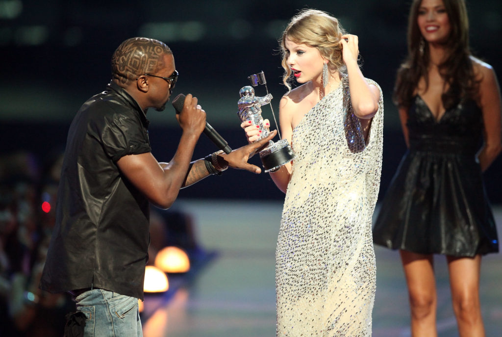 Kanye West (L) jumps onstage after Taylor Swift (C) won the "Best Female Video" award during the 2009 MTV Video Music Awards (Getty Images)